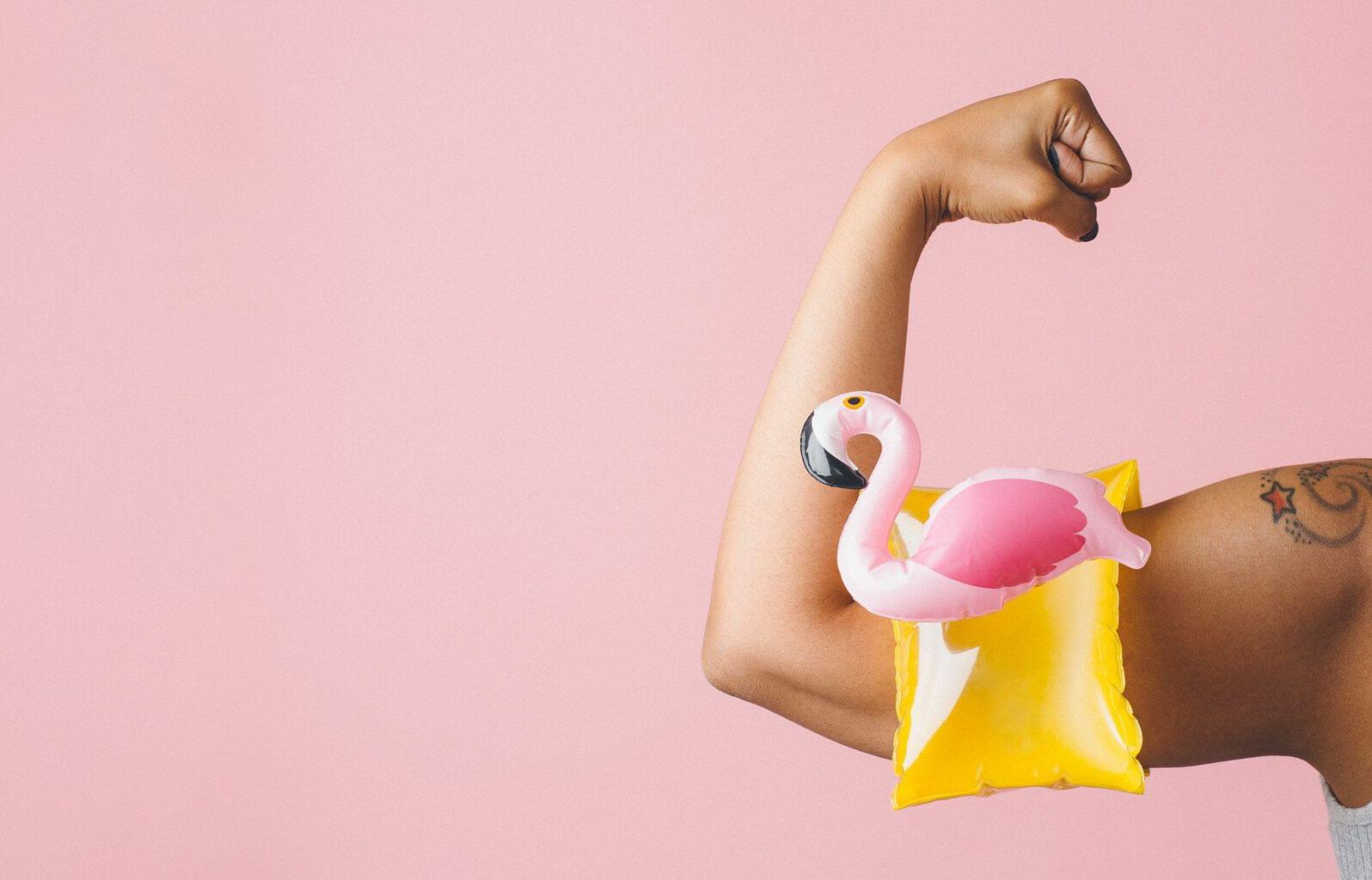 bicep flexing while wearing a flamingo pool floatie