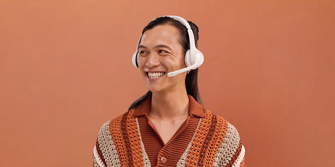 A man with a headset happily answers a customer call.