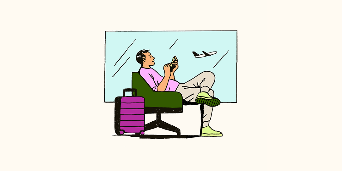 A man on a phone sits in a green chair next to a purple suitcase and a window with a plane taking off in the background.