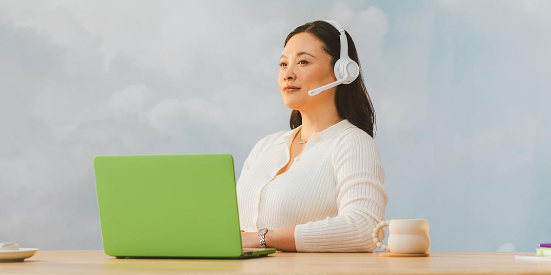 A call center customer service representative sits in front of a laptop