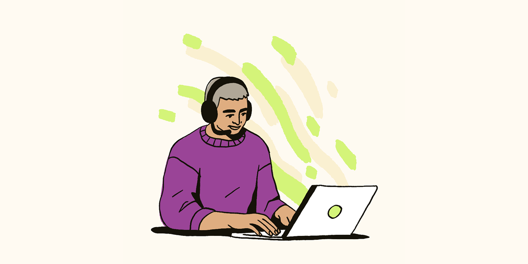 A man wearing a headset works on a laptop.