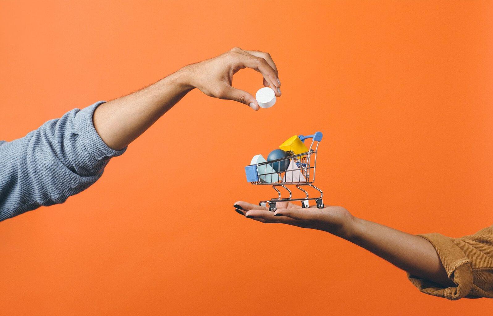 Shopping cart with hand adding items on orange background