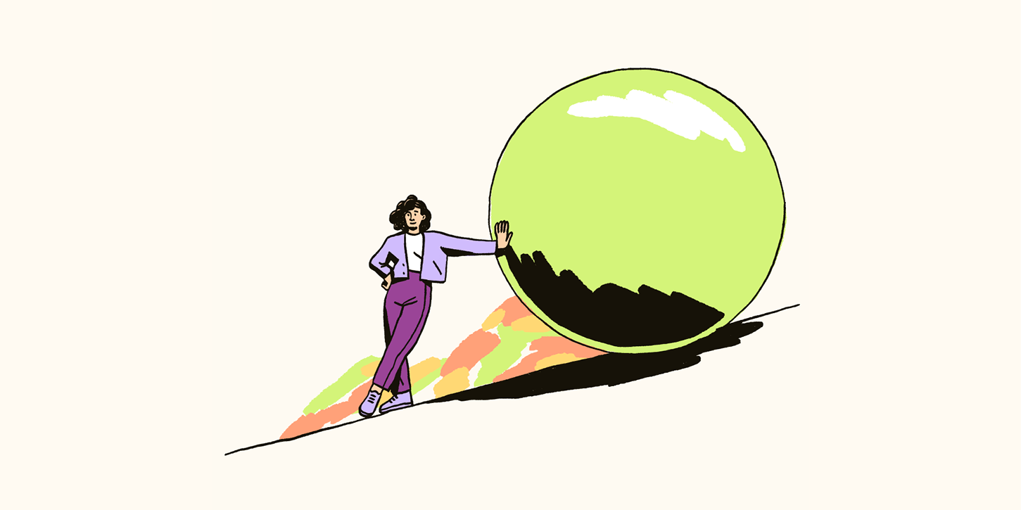 A woman pushes a large green ball up a hill. 