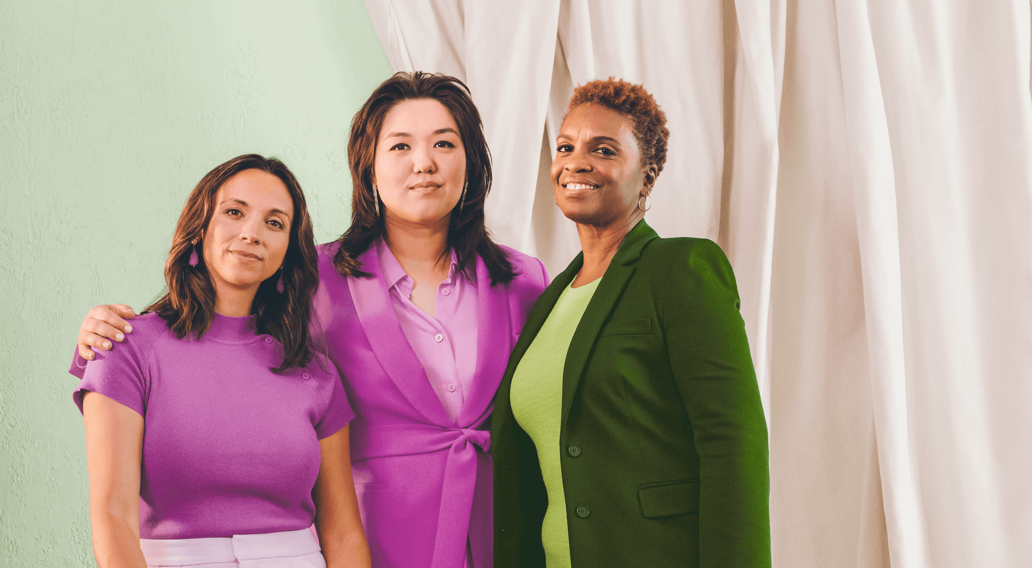 Three women in colorful blazers pose for a picture.