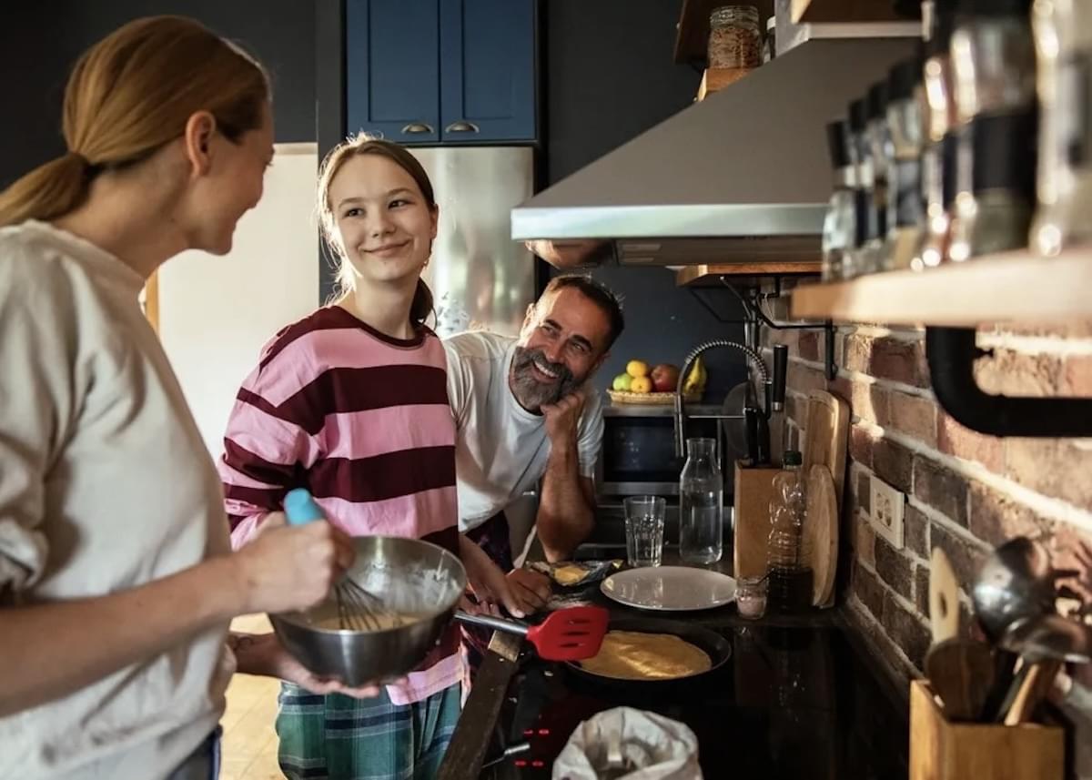 Pai, mãe e filha cozinhando