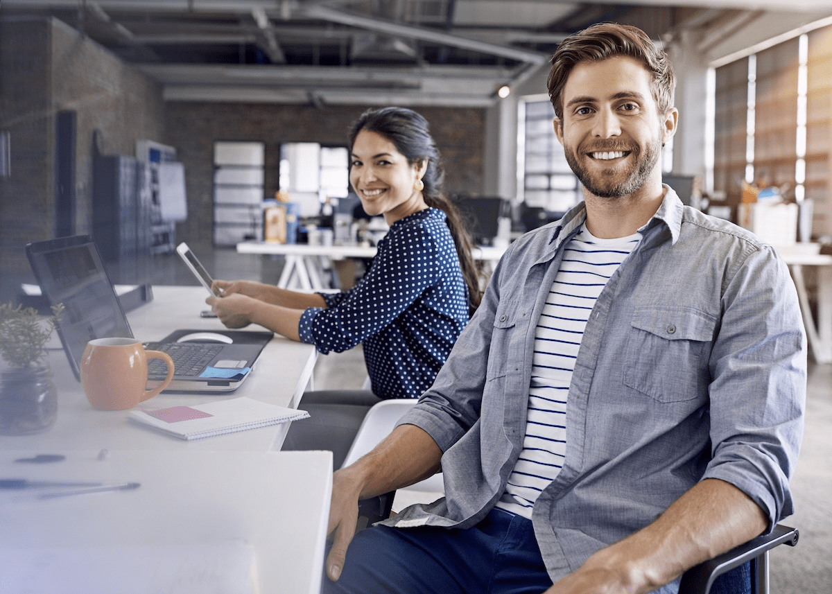 Smiling man and woman at computer work station