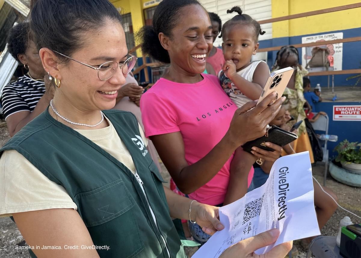 GiveDirectly staff helps Sameka register to receive emergency cash after Hurricane Melissa in Jamaica.