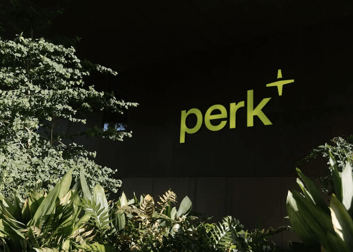 Light green Perk logo against a dark background with green plants in foreground