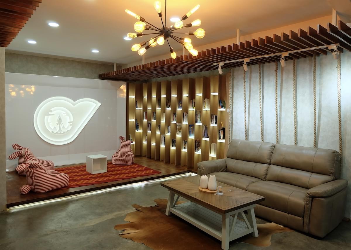 Reception area of Privy's office, decorated with a grey leather couch, coffee table, and cowhide rug; books on a lighted bookshelf, and a red chevron rug with three playful chairs