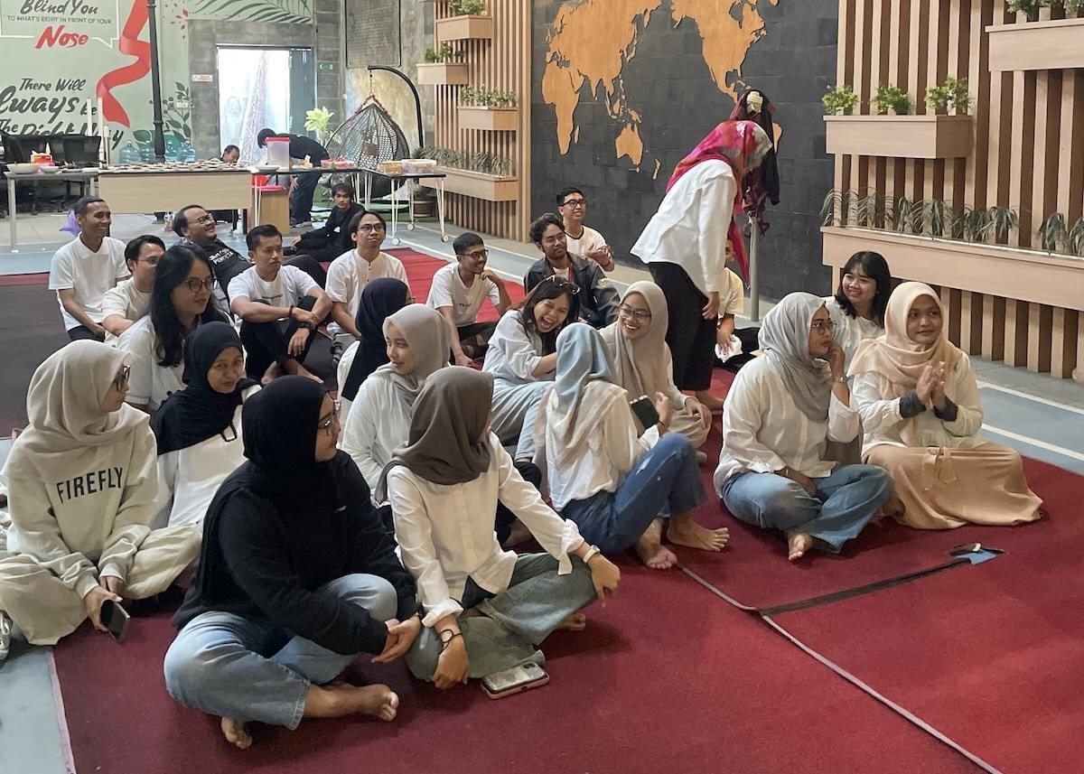 Privy employees sit cross-legged on on a red rug inside Privy's office