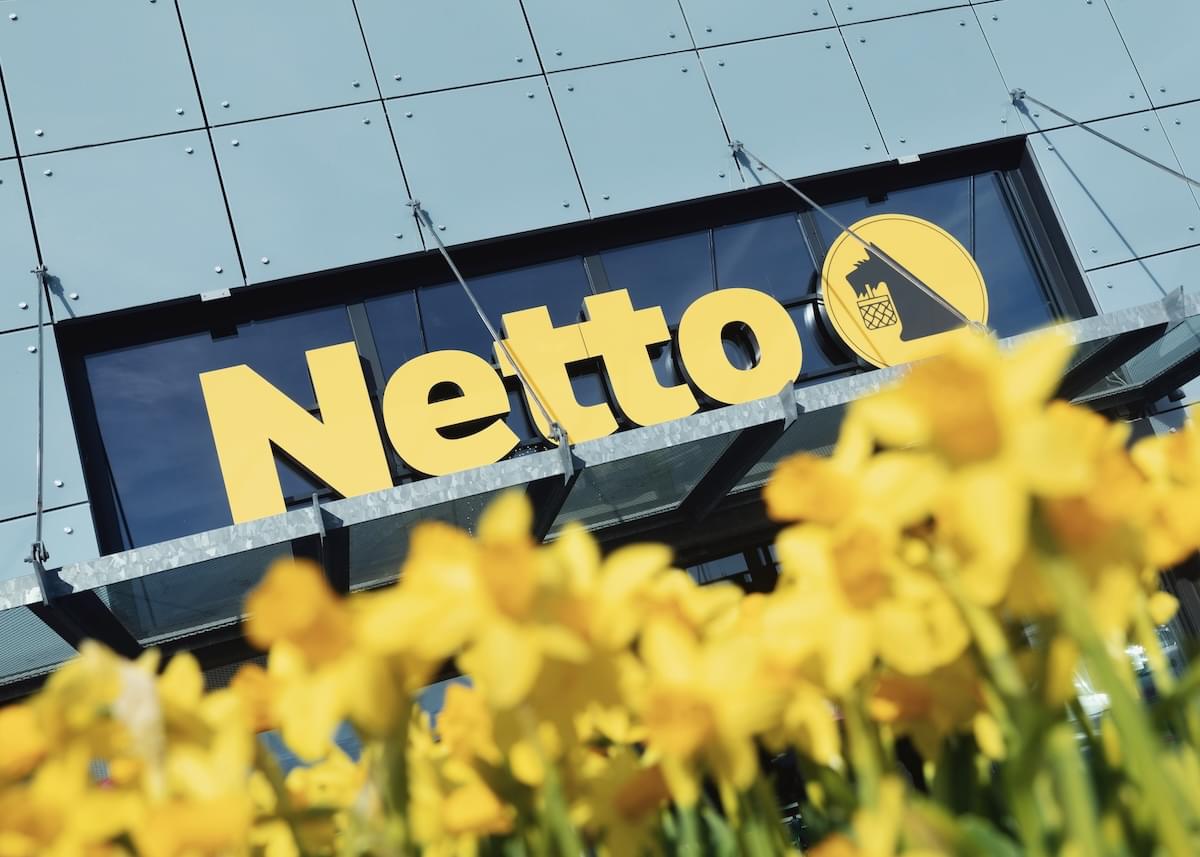Exterior of Netto with bright yellow daffodils in the foreground