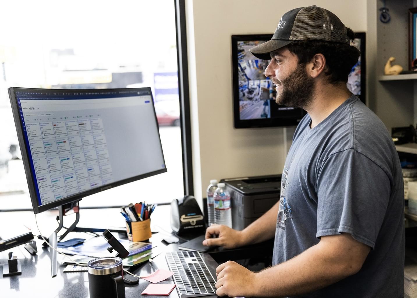 Inside an office, a man looks at the Shopmonkey website on his desktop computer.