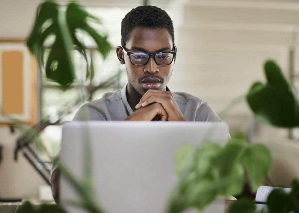 A man looks to be deep in thought, sitting in front of his laptop
