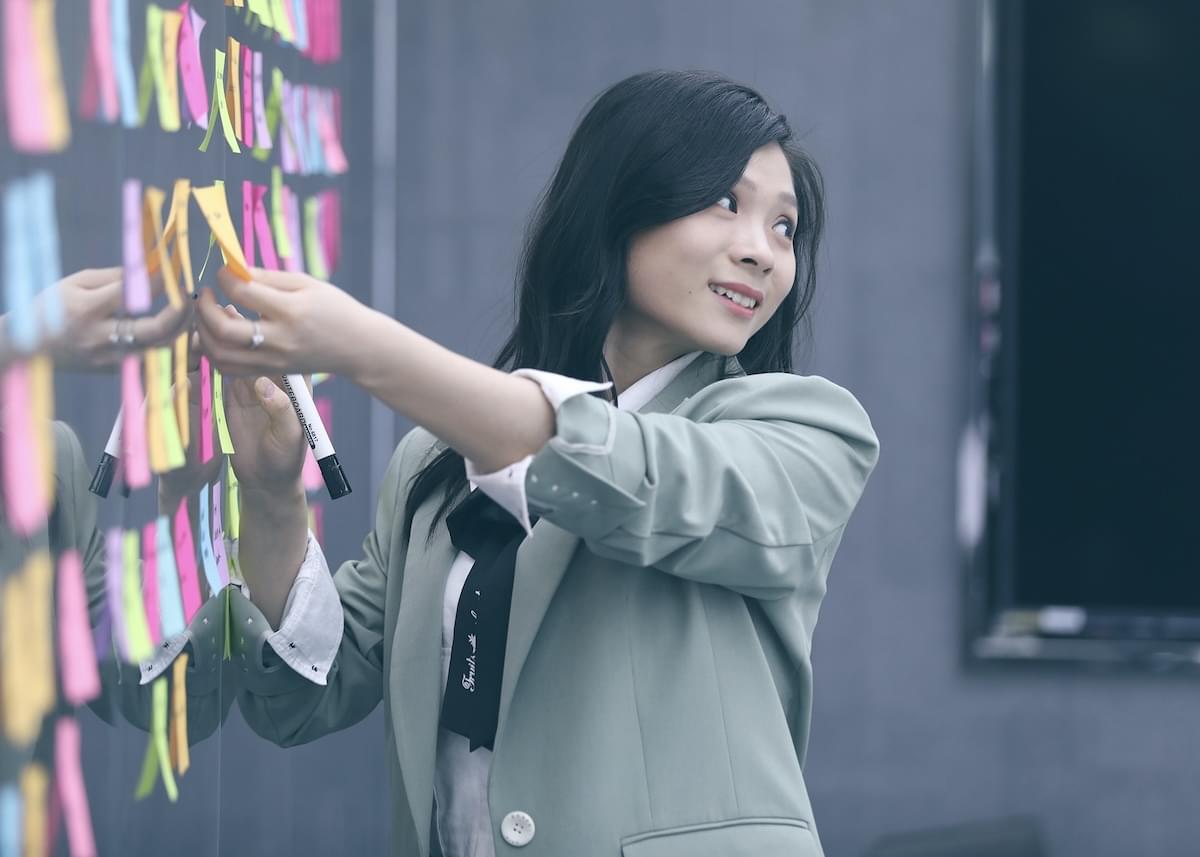 A young woman looks over her shoulder as she arranges several dozen brightly colored sticky notes
