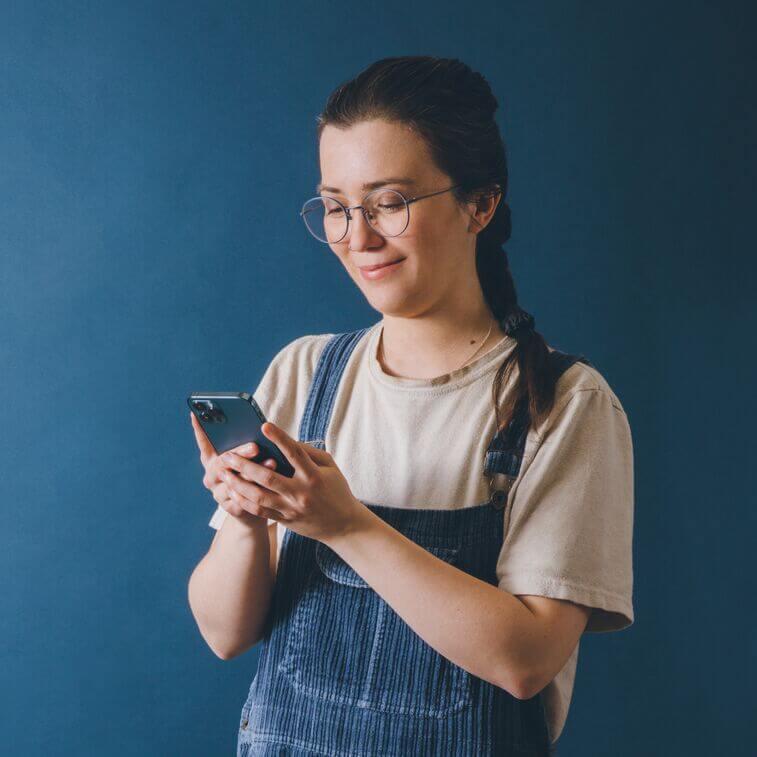 Woman holding smartphone and looking at her screen smiling