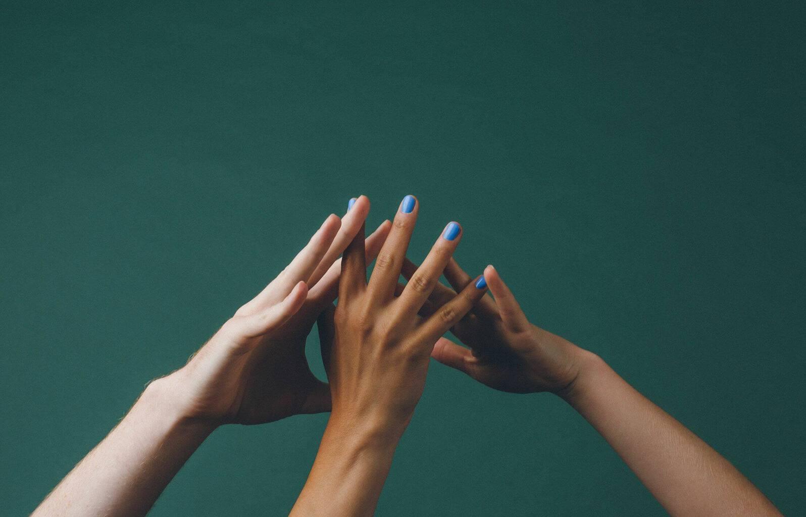 Three people with their hands together in a team huddle